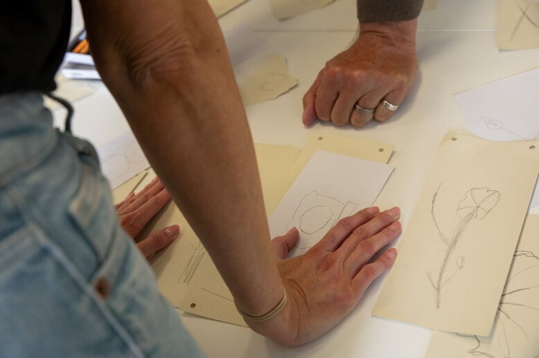 Menschen schauen auf einen Buchstaben sowie weitere Zeichnungen.