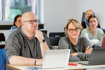 Mehrere Studierende unterschiedlichen Alters sitzen in einem Seminar und hören aufmerksam zu.