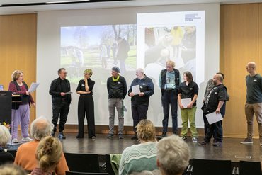 Einige Menschen stehen auf dem Podium vor einer Präsentation.