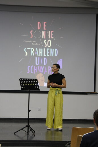 Chantal Fleur Sandjon steht am Pult und performt ihren Beitrag
