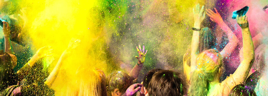 Menschen bei einem Holifest, in einer Wolke aus bunten Sprühfarben.