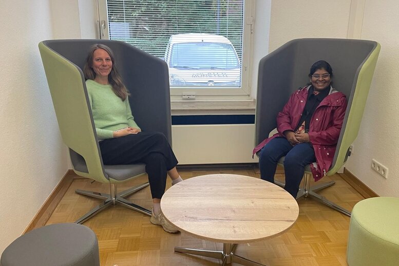 Zwei Personen sitzen auf futuristisch-modernen Ohrensesseln.