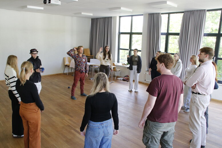 Im Seminarraum stehen alle Beteiligten im Kreis