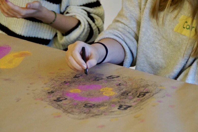 Eine Schüler:innen gestalltet mit einen Wachsmalbild ein Bild.