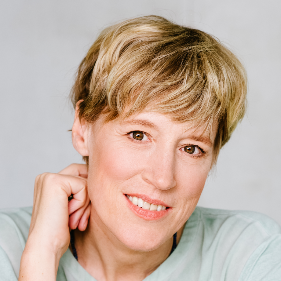 Eine Nahaufnahme von Ulrike Becker. Sie hat kurze blonde Haare und trägt ein helles Shirt.