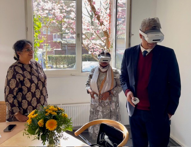 Ein Lehrender der Christ University hat eine Virtual Reality Brille auf, zwei indische Kolleginnen schauen ihm dabei zu.