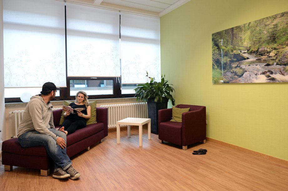 Eine schwangere Frau und ein Mann in einem Warteraum mit freundlicher Ausstattung.