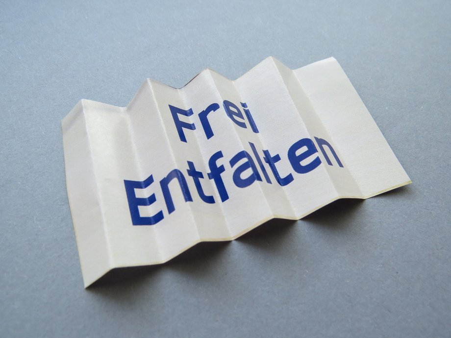 Ein entfaltetes Papier mit dem Aufdruck: Frei entfalten