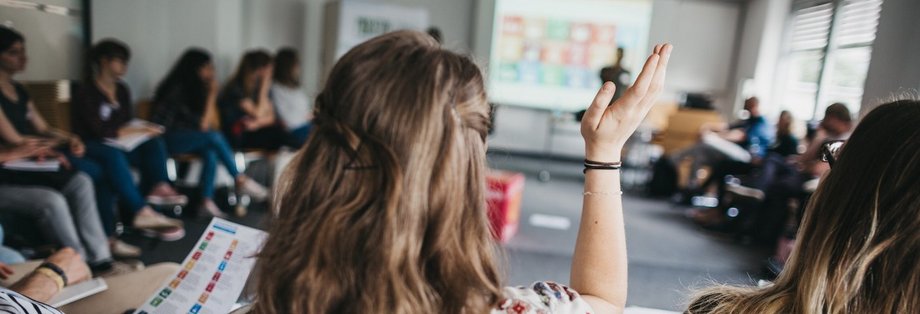 Studierende im Sitzkreis, eine Studentin meldet sich.