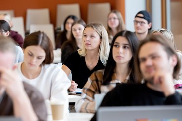 Mehrere Studierende sitzen in einem Seminar und hören aufmerksam zu.